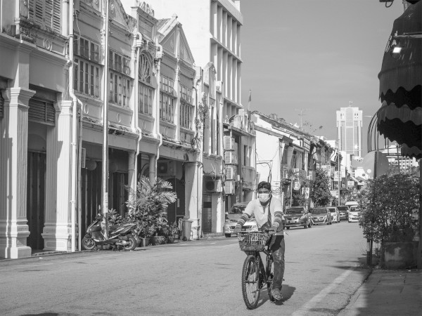 A lone man cycles along one of the empty streets in Penang. (Photo Credit: Kelvin-zyteng, Unsplash)